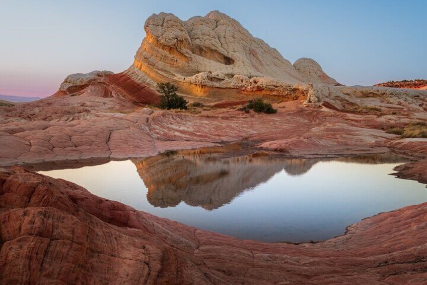 Un paysage désertique avec une grande formation rocheuse et une étendue d’eau qui reflète la lumière. 1