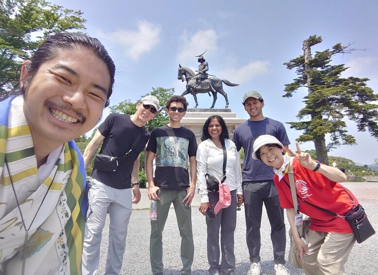 A group of people posing in front of a statue of a mounted figure. 1