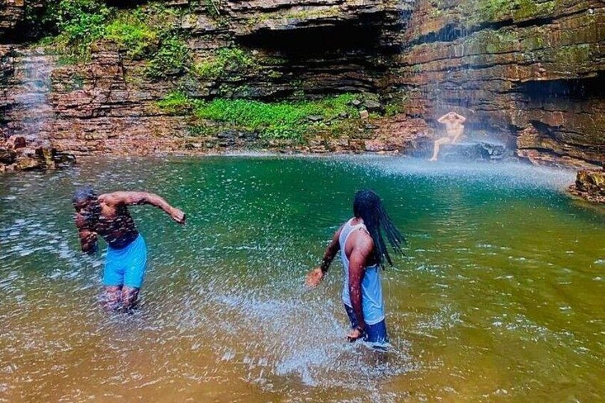 Two people in a natural water body with rocky surroundings. 5