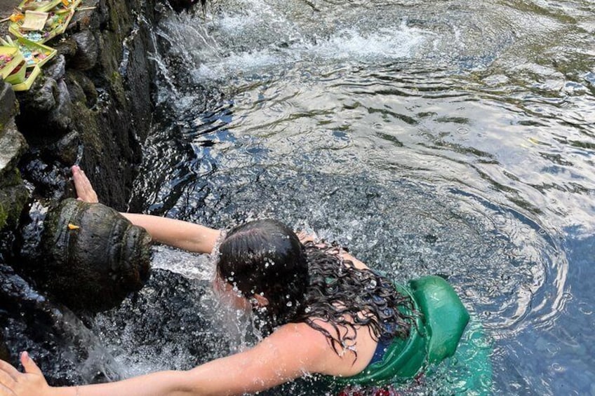 Iemand zwemt in een natuurlijke waterpoel met rotsen en begroeiing. 3