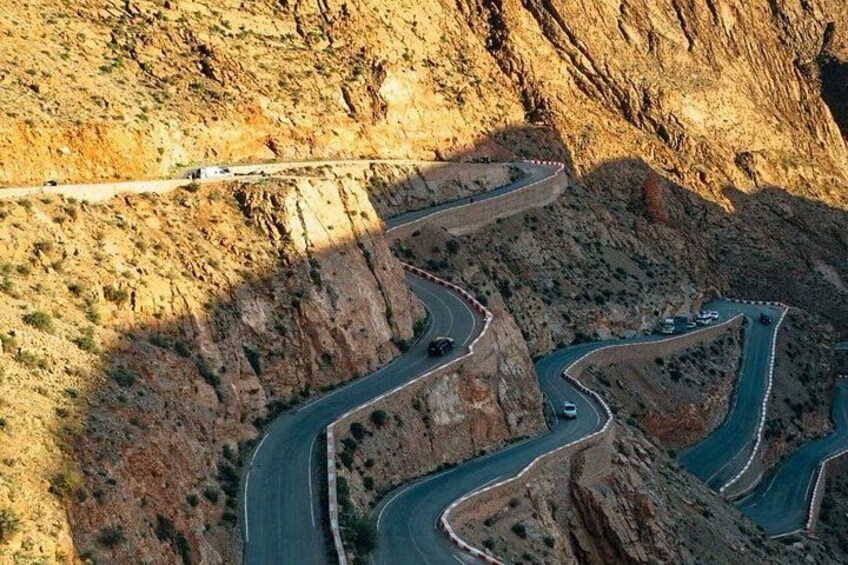 A winding mountain road with guardrails and vehicles. 2