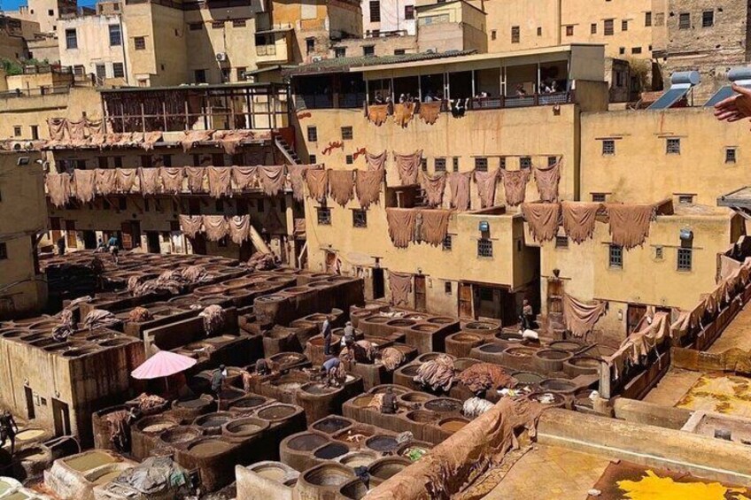 A traditional leather tanning area with large vats and drying cloths. 5