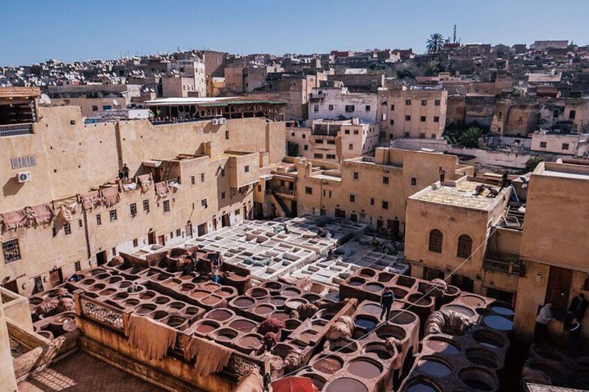 A traditional Moroccan medina with terracotta rooftops and a large open courtyard filled with clay pots. 4