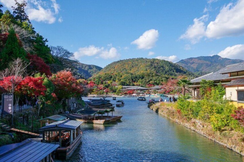 A river with boats, traditional buildings, and autumn foliage. 4