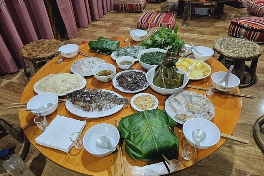 A round dining table with various dishes, including fish, vegetables, and sauces. 2