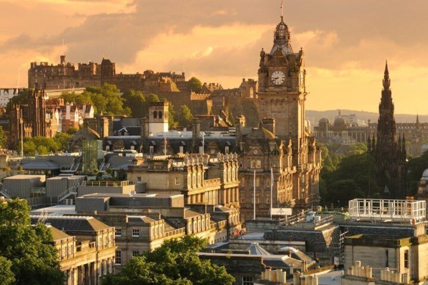 A cityscape with historic buildings, a prominent clock tower, and a castle in the background. 2
