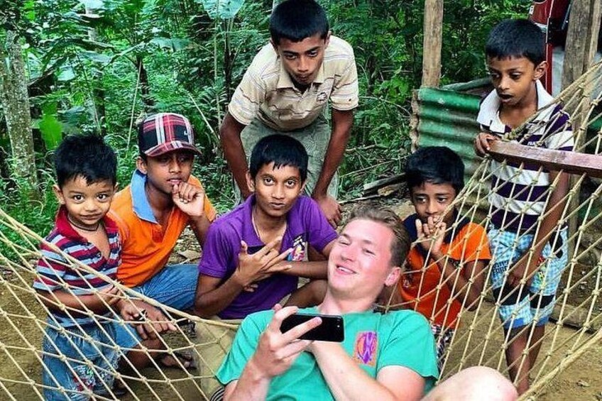 A group of people sitting on a rope bridge in a forested area. 2