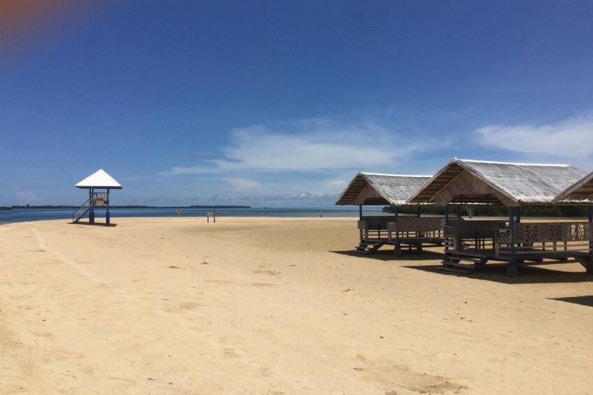 Una spiaggia con sabbia, una torretta di salvataggio e delle cabine. 1