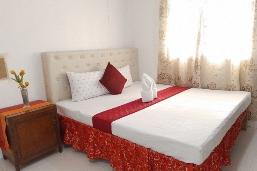 Un letto rifatto con cura, con copripiumino rosso, un cuscino bianco e un cuscino decorativo rosso. 5