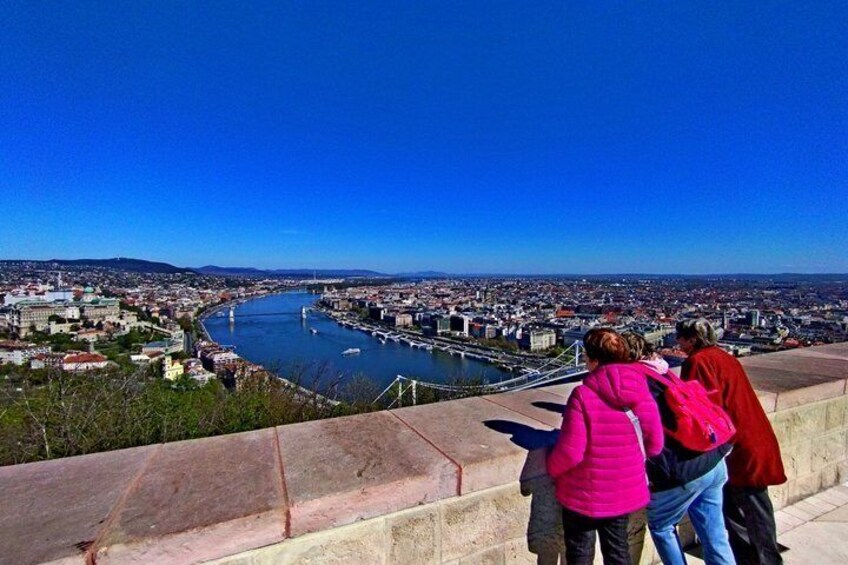 Un paisaje urbano con un río, un puente y un grupo de personas en una plataforma de observación. 2