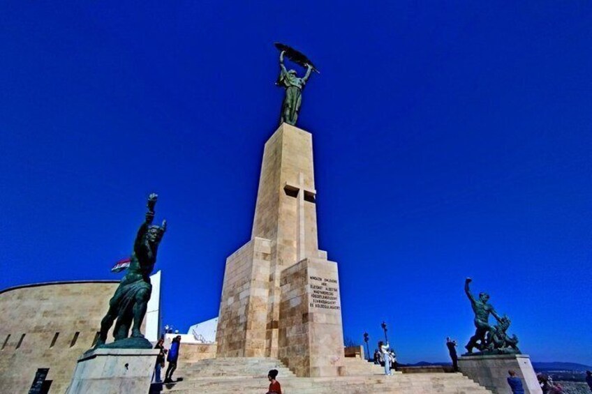 Un monumento con estatuas, un cielo azul despejado y una cordillera distante. 3