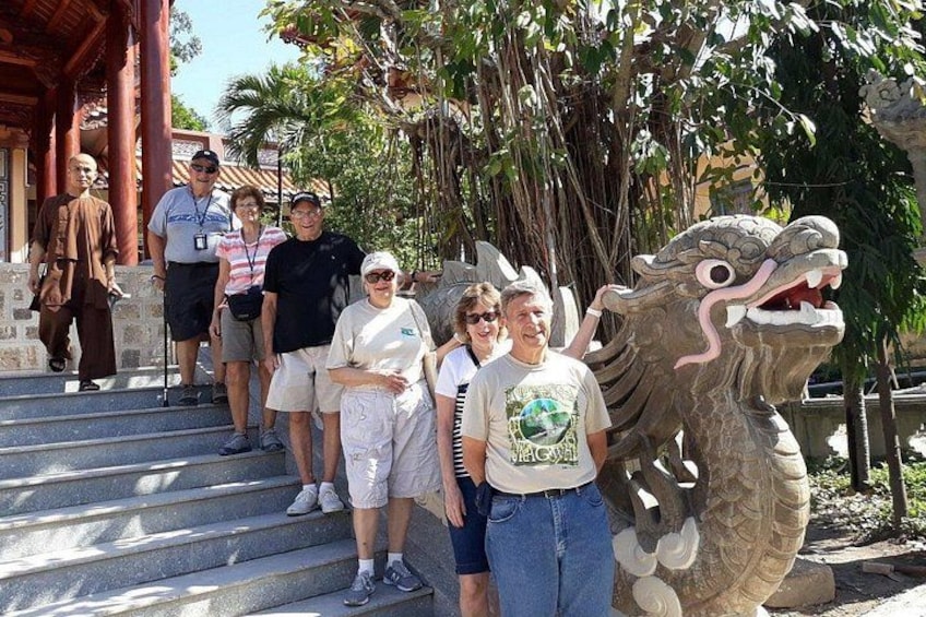Un grupo de personas de pie en unos escalones, con una gran estatua de dragón en primer plano. 3