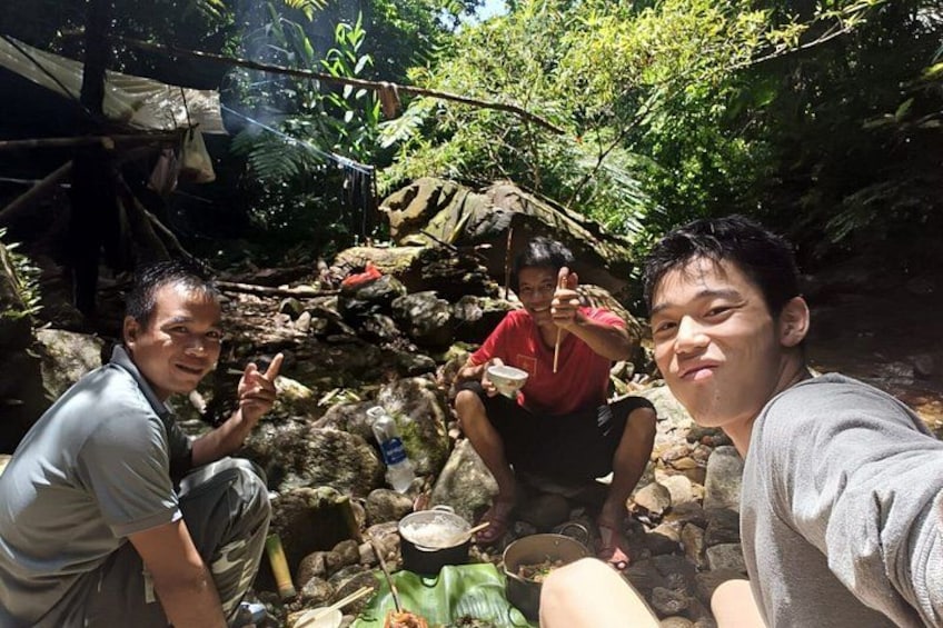 Tres personas sentadas al aire libre, con terreno rocoso y vegetación de fondo. 4