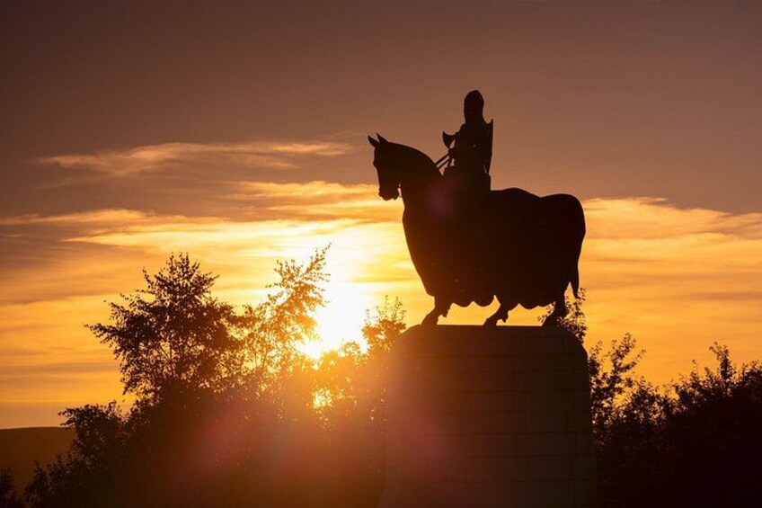 A statue of a person on horseback against a sunset. 2