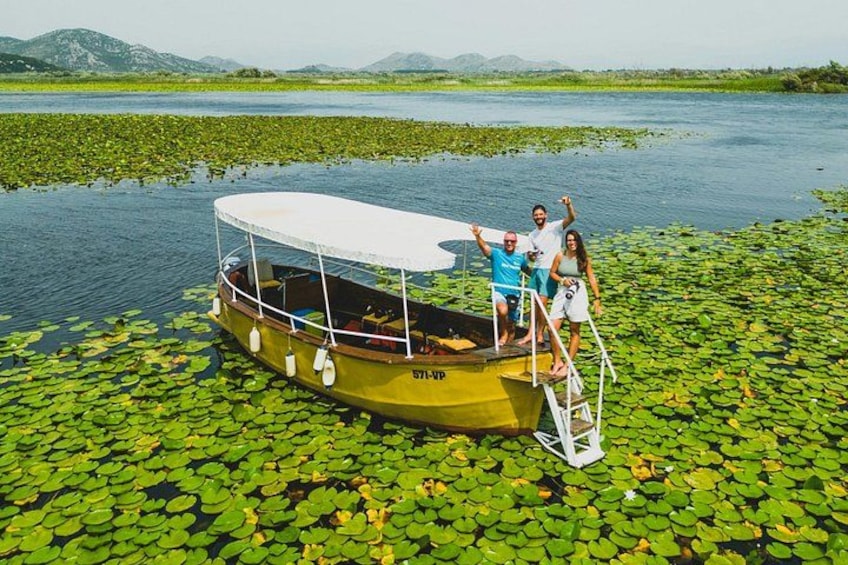 A boat with people on it, surrounded by water and lily pads. 2