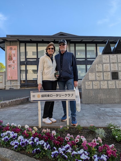 Two people standing in front of a building with a sign that reads 'Rotary Club.' 4