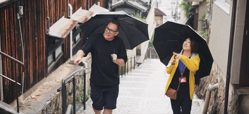 Two people walking down a narrow alleyway, each holding an umbrella. 2