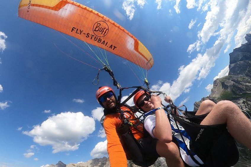Two people paragliding with a mountain landscape in the background. 1