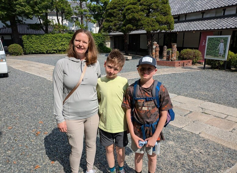Three people standing in front of a traditional building with a tiled roof. 2