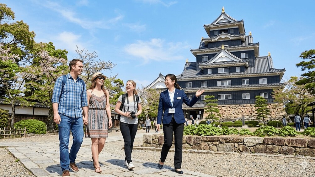 A group of people walking in front of a traditional Japanese castle. 1