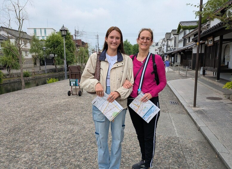 Two people holding maps in a historic town with traditional buildings and a canal. 4