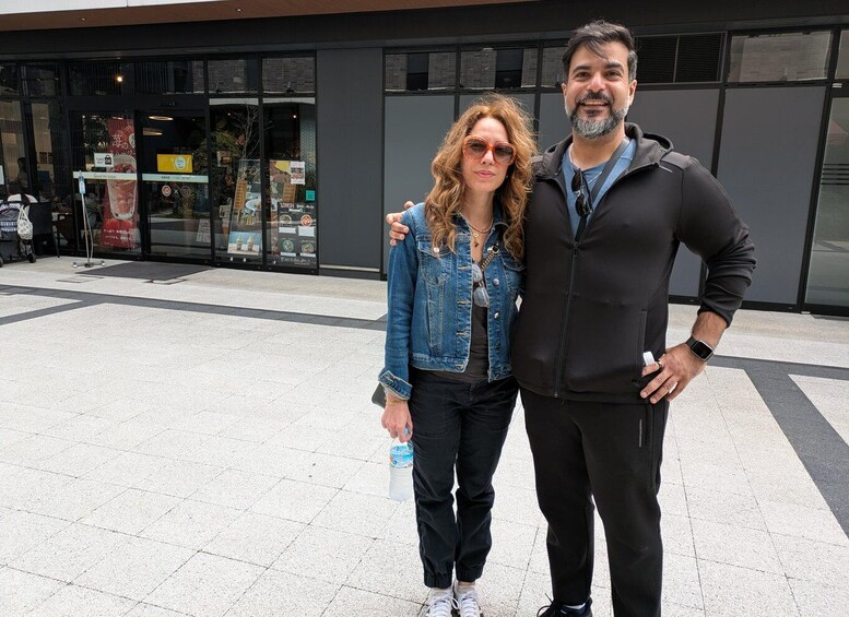 Two people standing in front of a building with glass windows and a tiled floor. 3