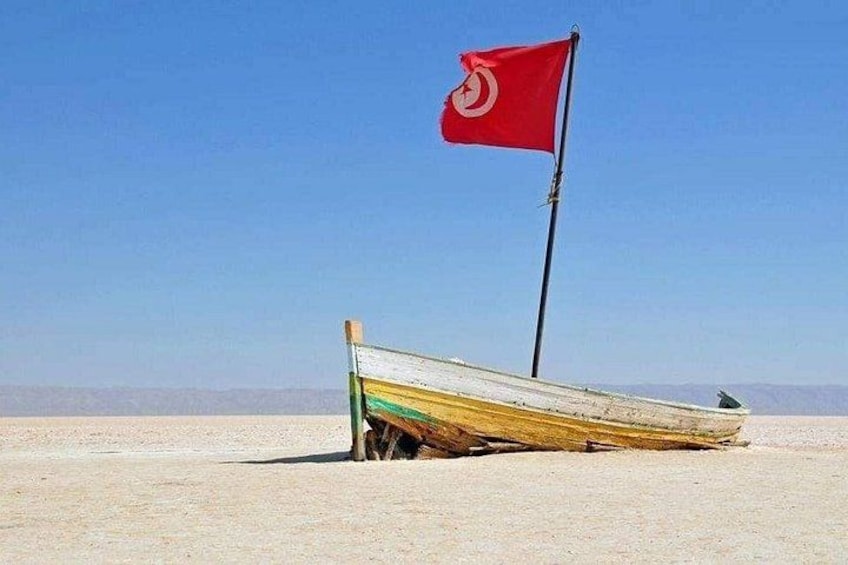 A boat on a sandy beach with a red flag. 1