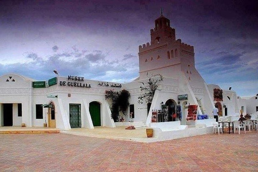 A white building with a tower, labeled 'Musee de Guellala,' and a paved plaza. 4