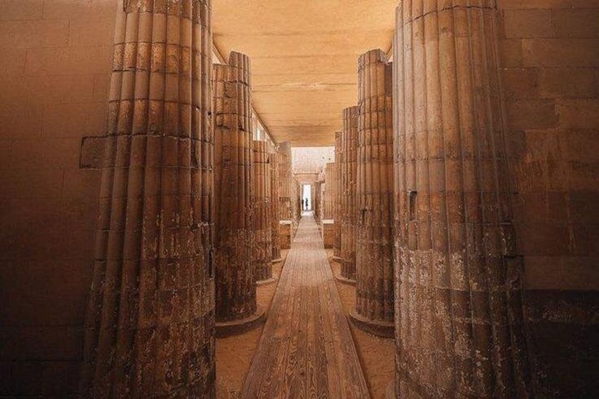 A corridor with large cylindrical columns and a wooden floor. 5