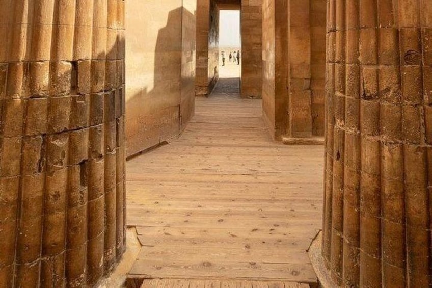 A wooden pathway flanked by bamboo walls leading to a distant structure. 3