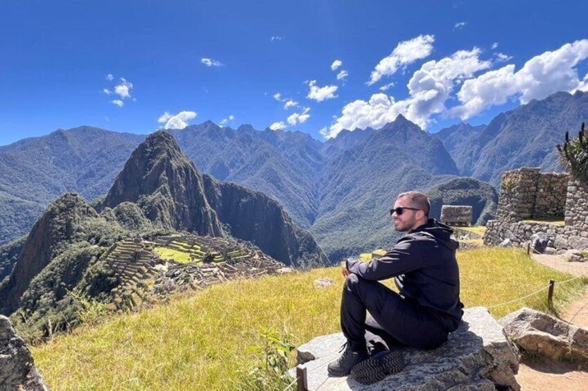 A person sitting on a rock with Machu Picchu ruins in the background. 2