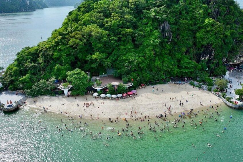 Ein Strand mit badenden und sonnenden Menschen, umgeben von üppiger Vegetation und einem angestoßenen Boot in der Nähe. 3