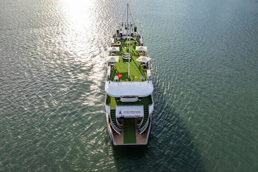 Ein großes Kreuzfahrtschiff mit grüner Deckfläche und mehreren Sonnenschirmen. 2
