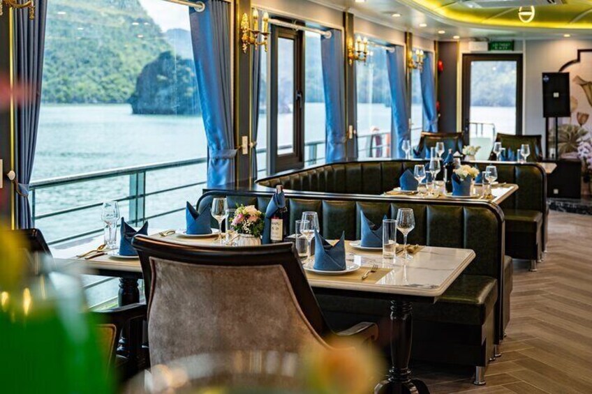 Ein Restaurant mit gedeckten Tischen, großen Fenstern mit Blick auf ein Gewässer und einer Aussicht auf eine Berglandschaft. 3