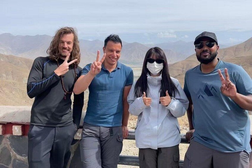 Four people posing with peace signs in a desert landscape. 2