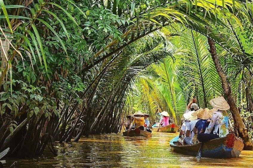 A river surrounded by dense tropical vegetation with people in small boats. 2