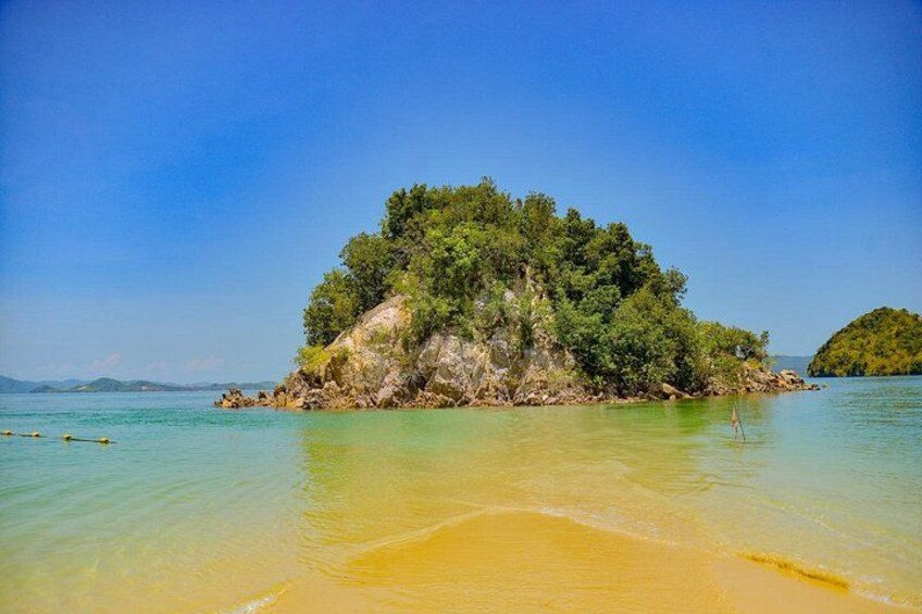 A tropical island with clear turquoise waters, sandy beach, and lush green vegetation. 5