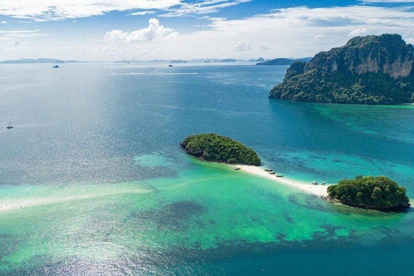 A tropical island surrounded by clear turquoise waters, a sandy beach, and lush greenery. 4
