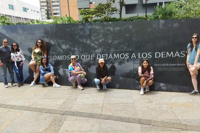 Un grupo de personas sentadas y de pie frente a una pared con texto. 5