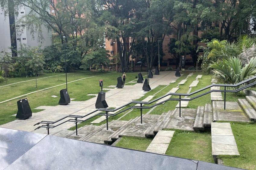 Un parque con una escalera de piedra, césped, árboles y un edificio al fondo. 4