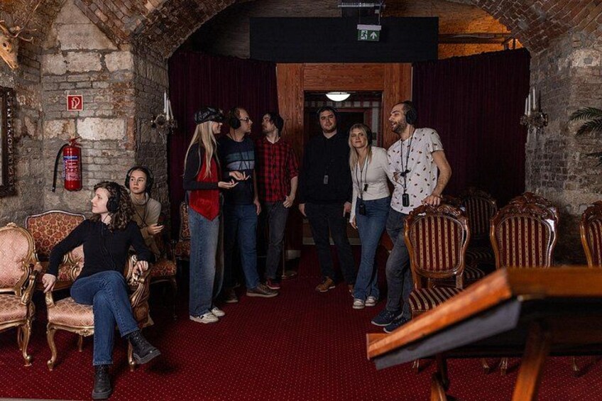 Un grupo de personas en una habitación rústica con paredes de ladrillo, sillas de madera y una alfombra roja. 2