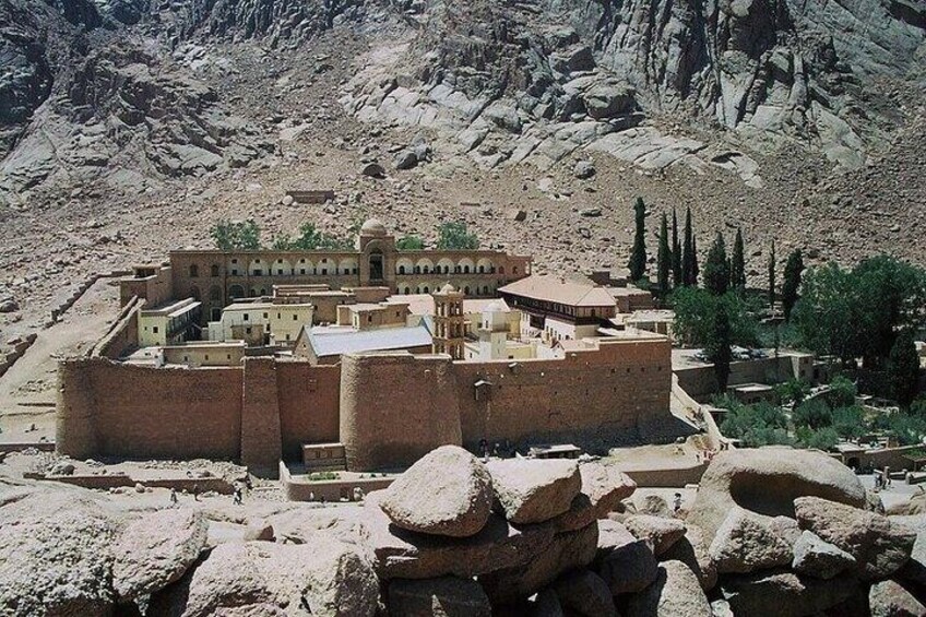 A historic walled city with ancient architecture, surrounded by rocky terrain and sparse vegetation. 1