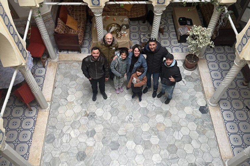 Un grupo de personas de pie en un patio con suelo de baldosas y un tapete estampado. 1