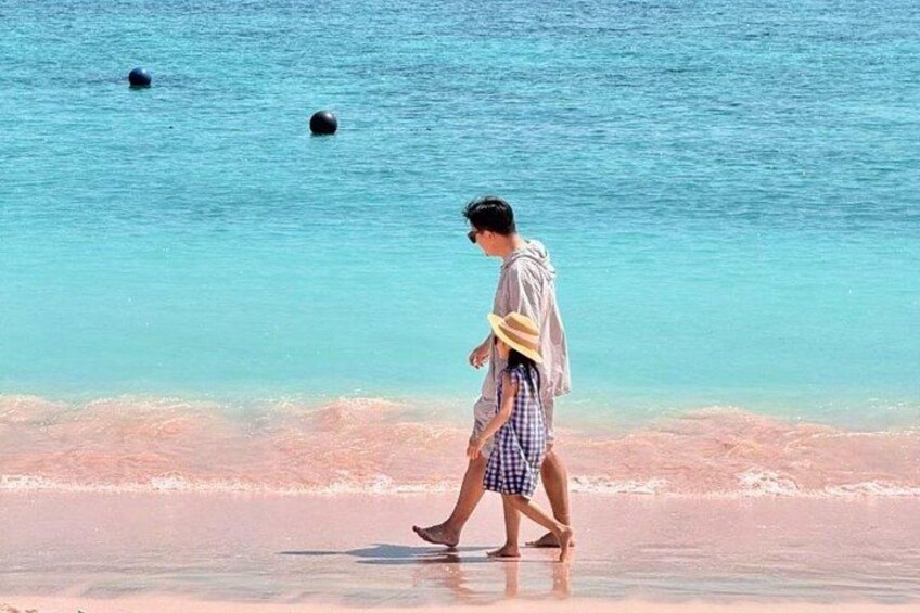 Una persona che cammina sulla spiaggia, con acque limpide e un mare calmo sullo sfondo. 2