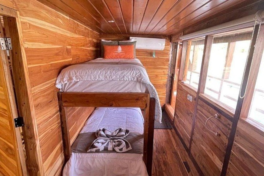 A wooden cabin interior with bunk beds and a window. 2