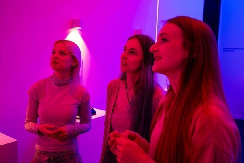 Trois personnes se tiennent à l’intérieur, éclairées par une lumière violette. 4