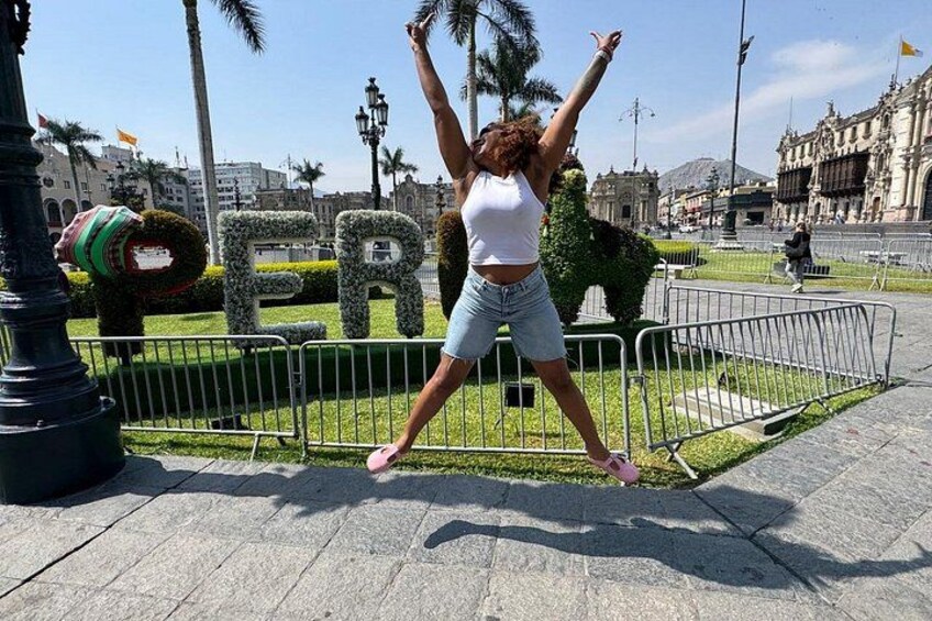 Una persona salta en una plaza pública con vegetación y un edificio al fondo. 5