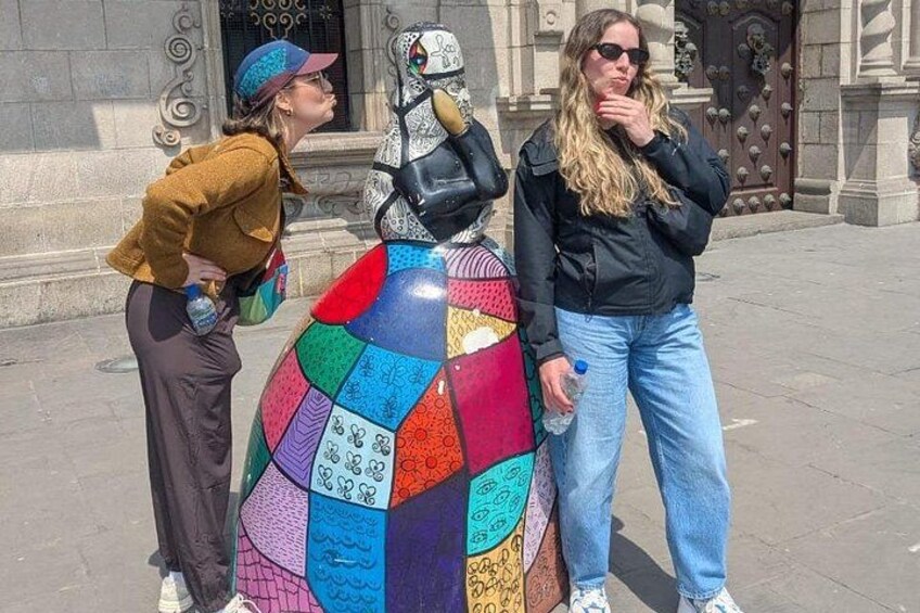 Dos personas de pie junto a una llamativa escultura de mosaico. 3