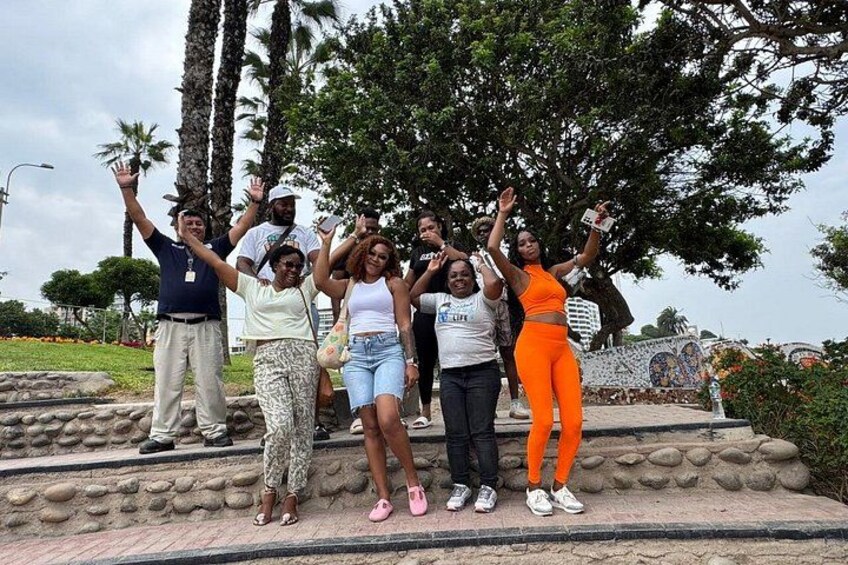 Un grupo de personas posando sobre una plataforma de piedra, con árboles y un mural de fondo. 4