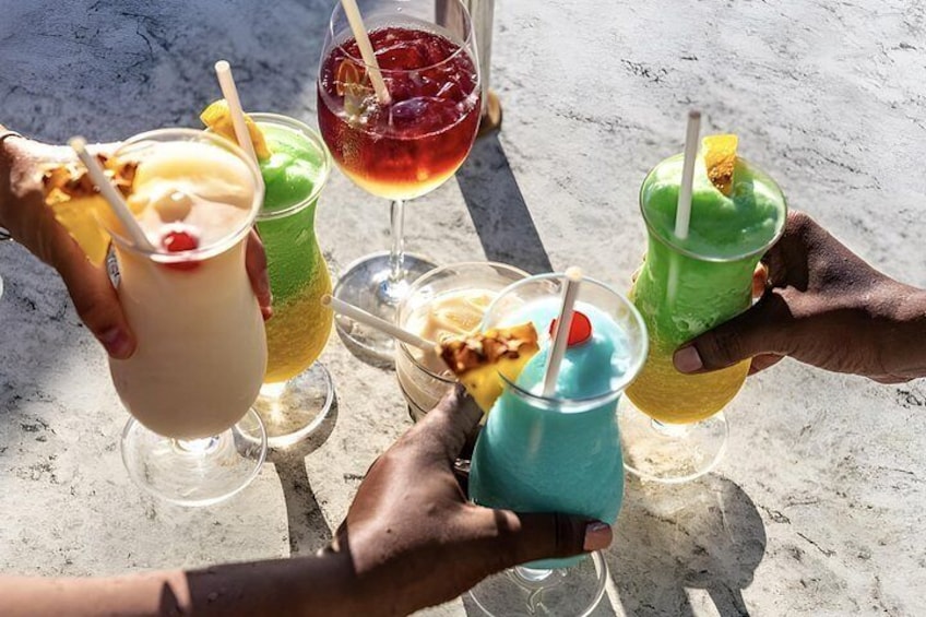 A group of people holding colorful drinks with straws, possibly at a beach or outdoor setting. 4